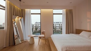 Una habitación de hotel moderna con una cama grande, una mesa redonda, una silla y un espejo.