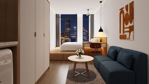 Una habitación de hotel moderna con vista a la ciudad, un sofá, una mesita y una lámpara.