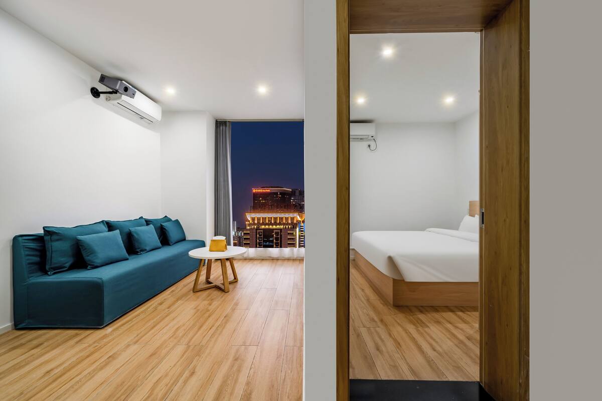 Een moderne hotelkamer met een bank, een klein tafeltje en een bed.