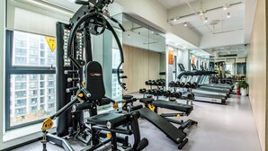 Un gimnasio moderno con diversos equipos de ejercicio, como máquinas de pesas y cintas de correr, dispuesto en un espacio amplio.