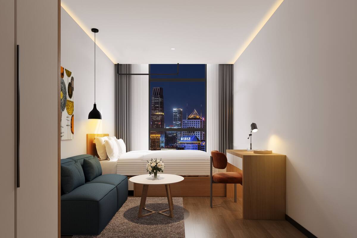Een moderne hotelkamer met uitzicht over de stad, een bank, een bureau en een bed.