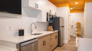 A modern kitchen with white cabinets, a stainless steel refrigerator, a microwave, and a dishwasher. - BRAND NEW 4 Deluxe Studios w/ Balcony in 12 South (Nashville)