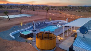 Un complexe hôtelier situé dans le désert, doté d’une piscine, d’un jacuzzi et d’un espace extérieur aménagé pour se détendre.