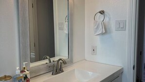 A bathroom with a white sink, a mirror, and a towel rack.