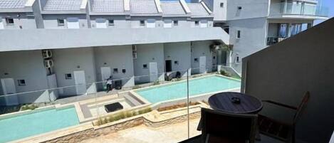A balcony with a view of a swimming pool and a building with a tiled roof.