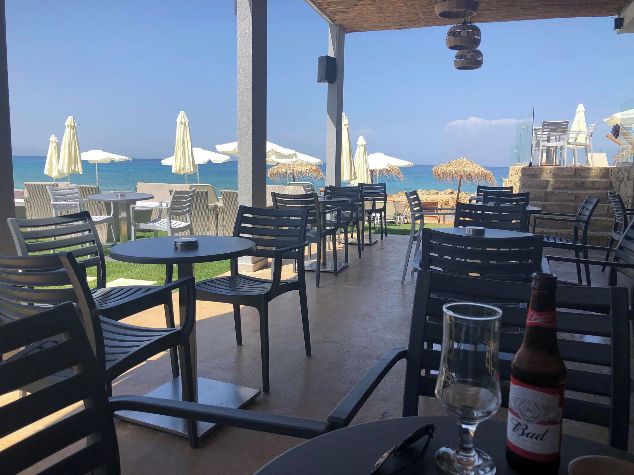Un espacio al aire libre con mesas y sillas, con vista al mar.