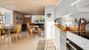 Une cuisine moderne avec des armoires blanches, un plan de travail en bois et un four encastré.