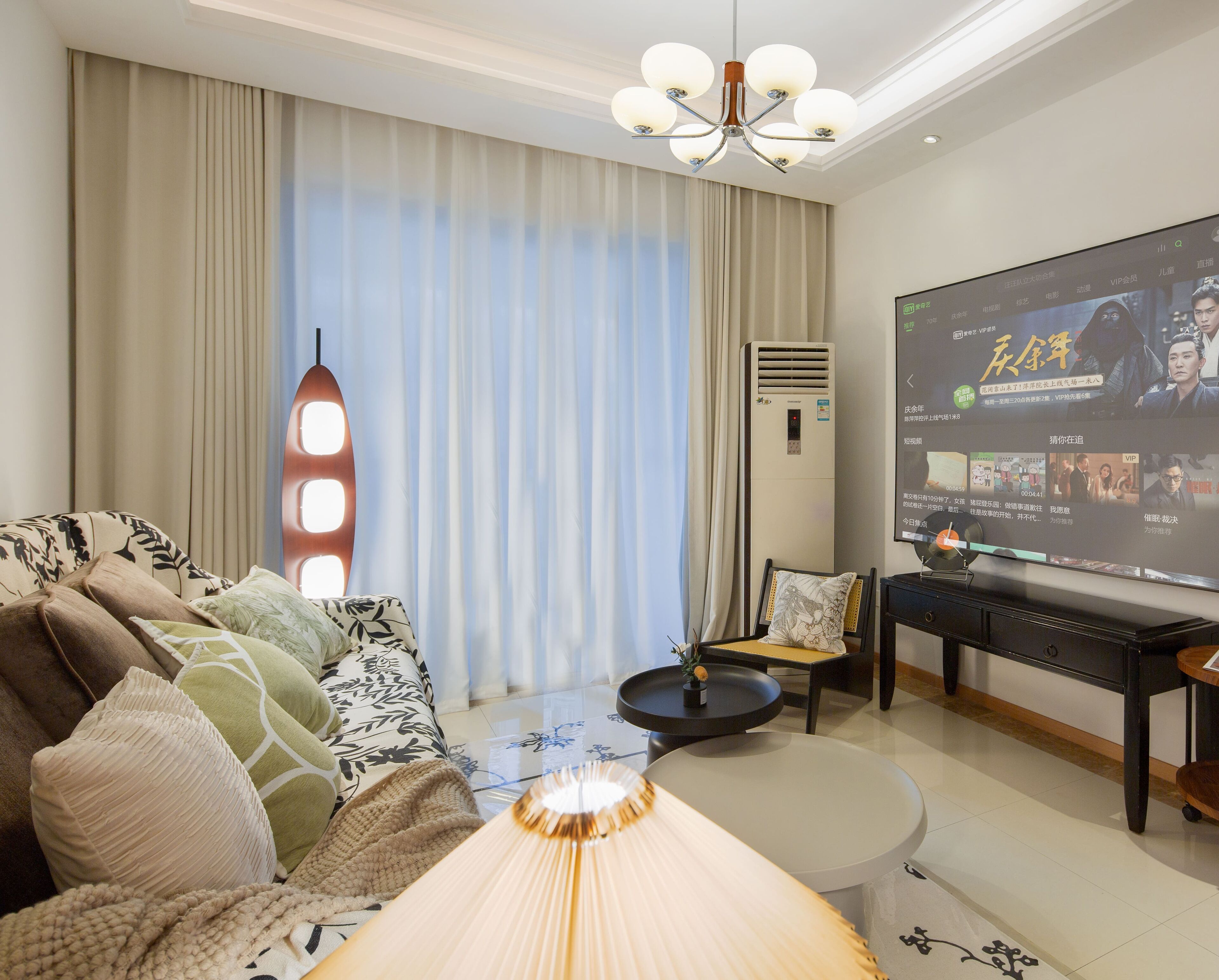 A modern living room with a sofa, a coffee table, and a TV displaying a movie.