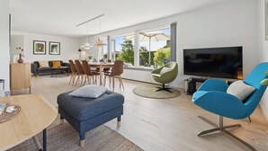 Un soggiorno moderno con un divano, poltrone, un tavolo da pranzo e una TV.
