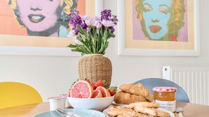 Ein Esstisch mit Obstschale, Croissants und Marmeladenglas.