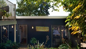 Un edificio con fachada oscura, un letrero de peluquería para mujeres y un balcón con plantas.