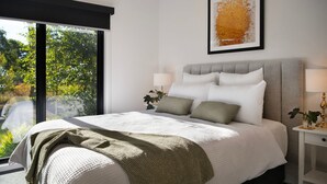 A modern bedroom with a large bed, a nightstand, a lamp, and a framed artwork above the bed. - Cosy Edge Studio-Modern stuido, quiet and walking distance to Farmers Arms Hotel (Daylesford)