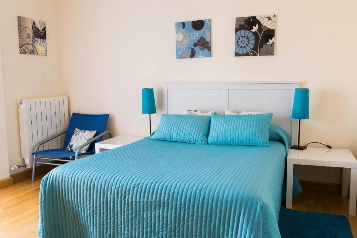 Ein Schlafzimmer mit einem Bett, einem Sessel, einem Nachttisch und zwei Wandleuchten.