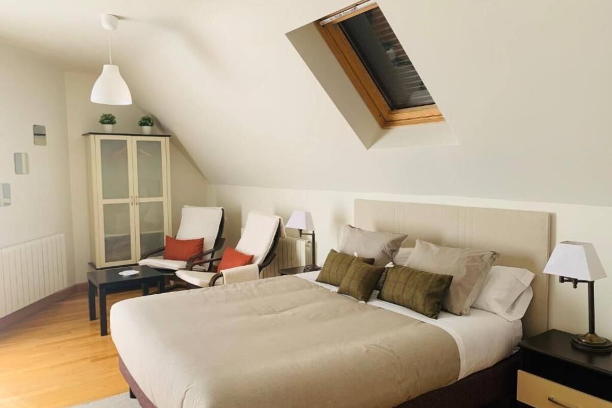 Ein Schlafzimmer mit einem großen Bett, einem Nachttisch, einem Sessel, einem Schrank und einem Fenster mit Blick.