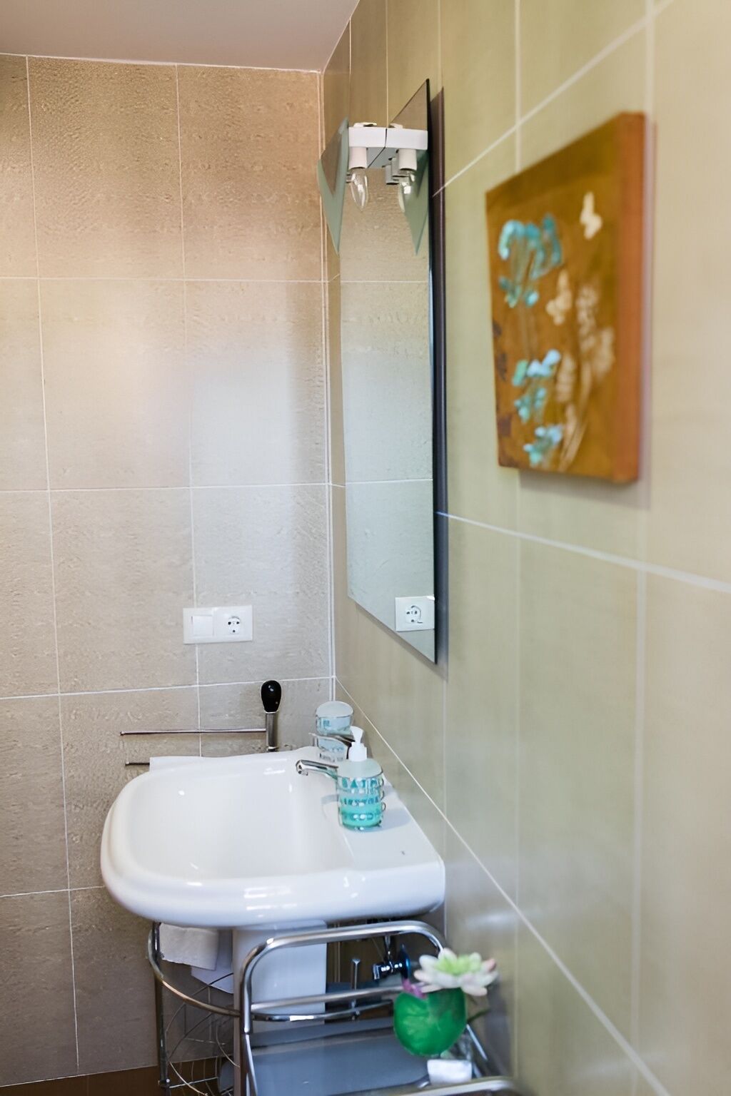 A bathroom with a white sink, a mirror, and a wall-mounted light fixture.