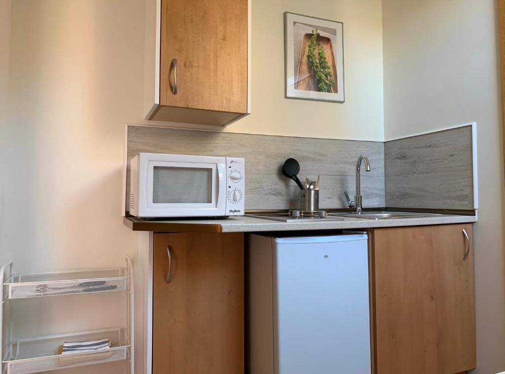 A compact kitchen with a microwave, sink, and wooden cabinets.
