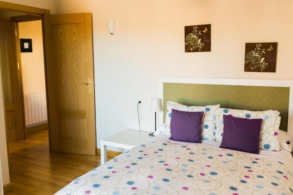 Un dormitorio con una cama, una mesita de noche y una puerta.