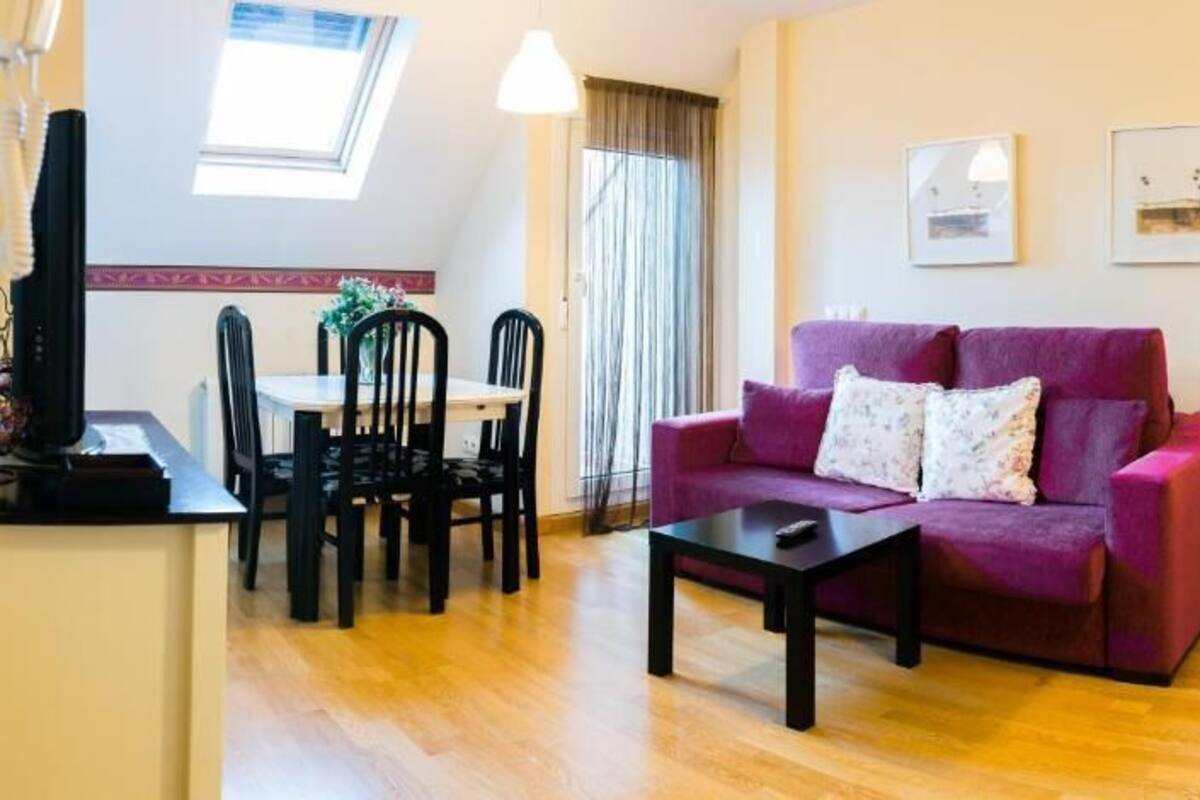 Ein Wohnzimmer mit einem violetten Sofa, einem Couchtisch und einem Essbereich mit Stühlen und einem Tisch.