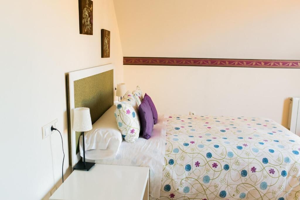 Una habitación de hotel con una cama, una mesita de noche y una lámpara.