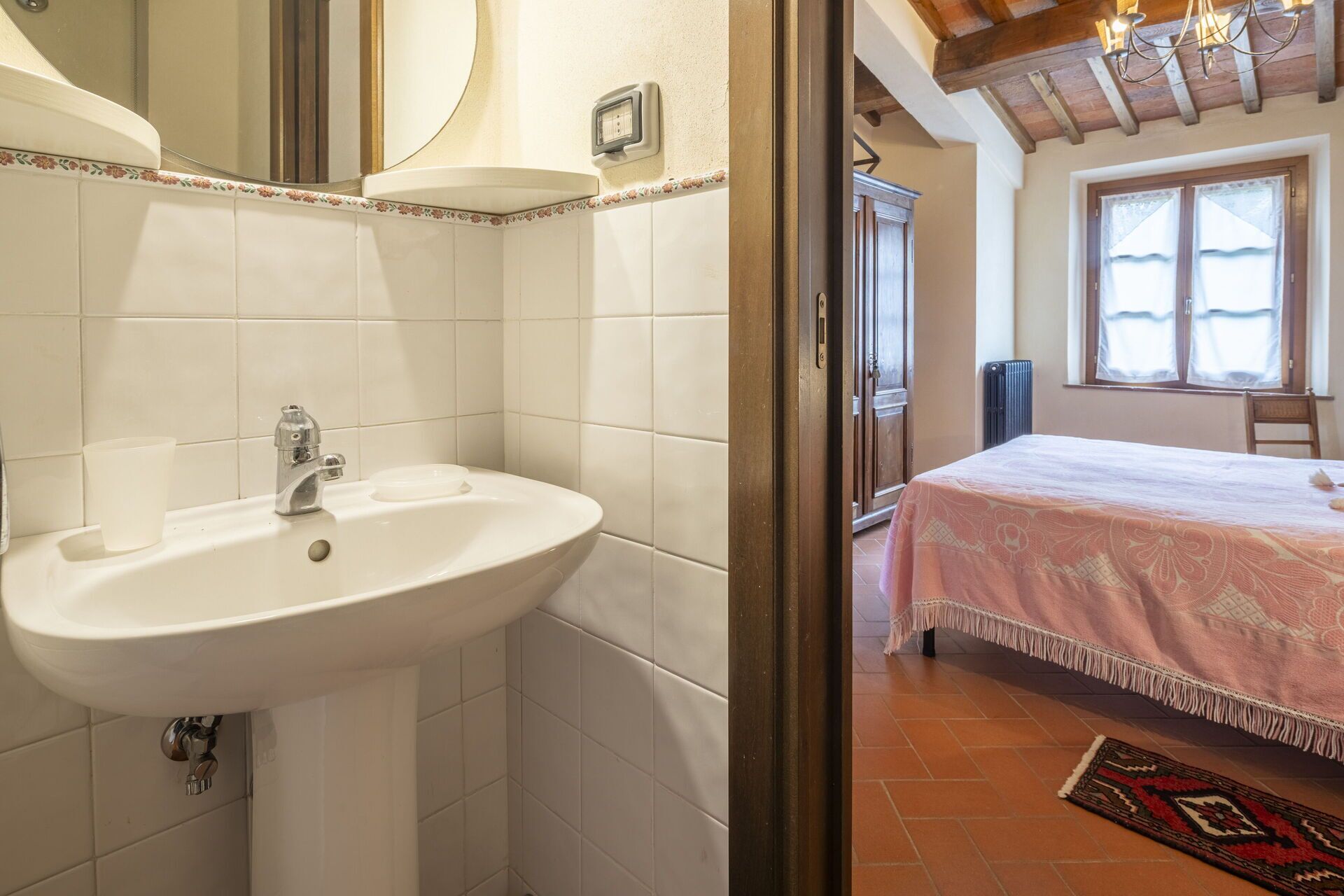 A bathroom with a sink, mirror, and a window with a view of the outside.