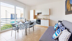 A modern apartment with a balcony, a dining area, a kitchen, and a living room.