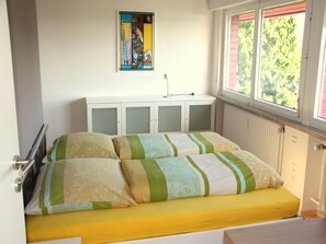 A bedroom with a bed, a radiator, a window, and a cabinet.