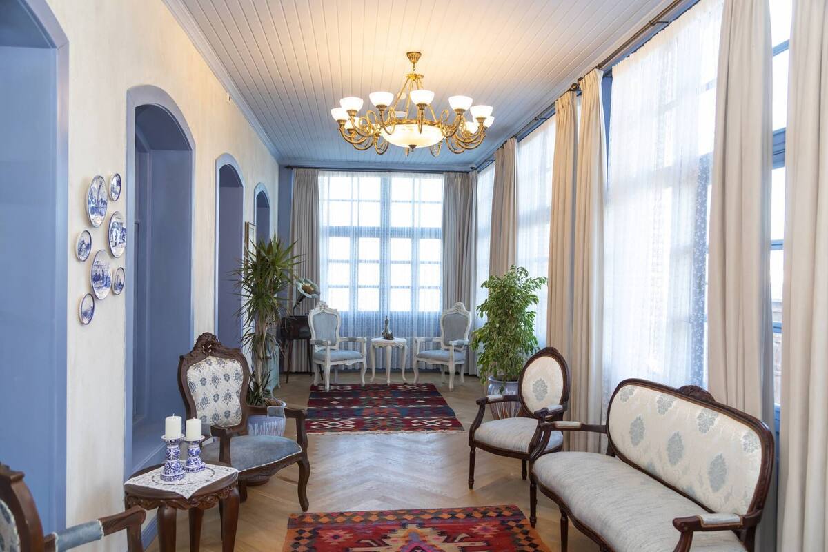 Una habitación amplia con candelabro, dos sillas, una mesa con vela y una alfombra estampada.