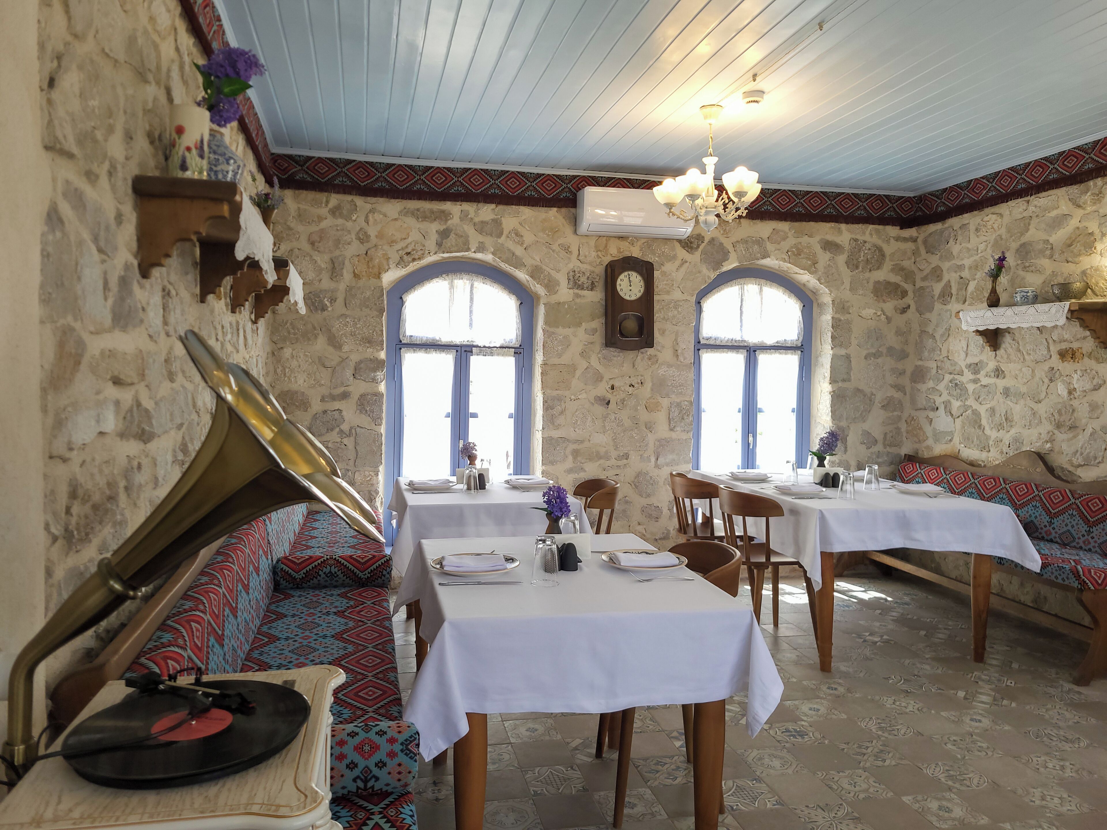 A dining area with stone walls, patterned benches, and tables set for two.