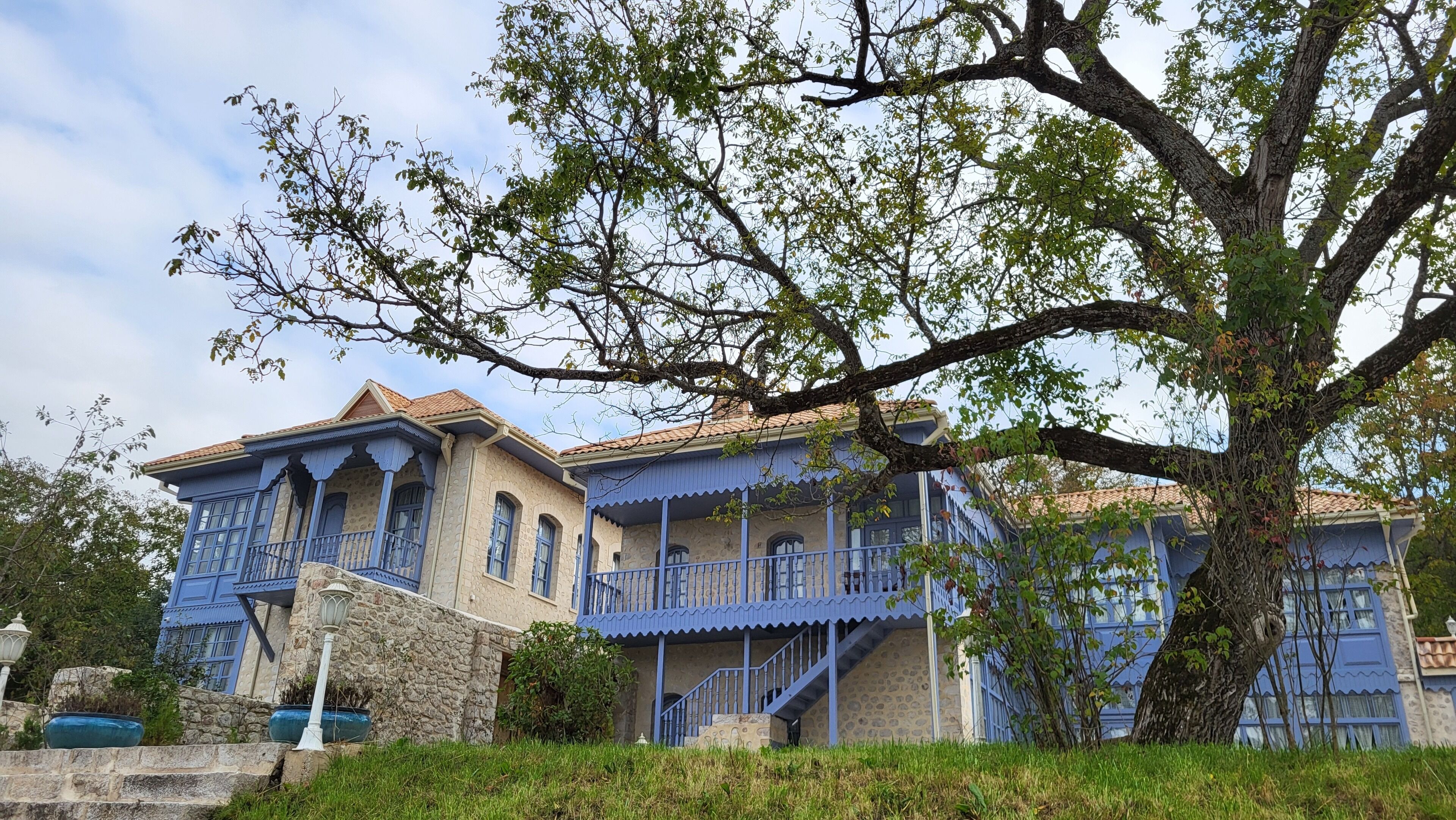 A traditional building with a stone facade, blue accents, and a staircase leading to a balcony.