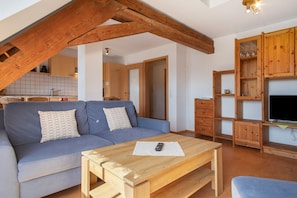 Un salon comprenant un canapé, une table basse en bois et un meuble TV avec des étagères.
