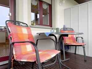 Un coin repas avec des chaises en métal et une table, une fenêtre ornée de rideaux en dentelle et un buffet blanc.