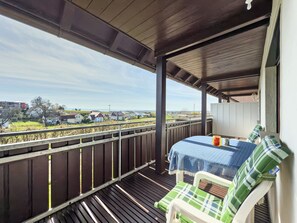 Un balcon donnant sur des maisons, une table recouverte d’une couverture et une chaise.
