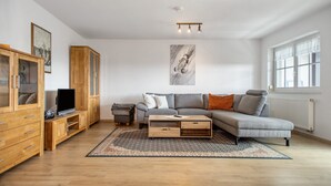 A modern living room with a sofa, wooden cabinet, television, and artwork on the wall.