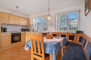 Uma cozinha moderna com armários de madeira, uma mesa de jantar com toalha azul e um banco.