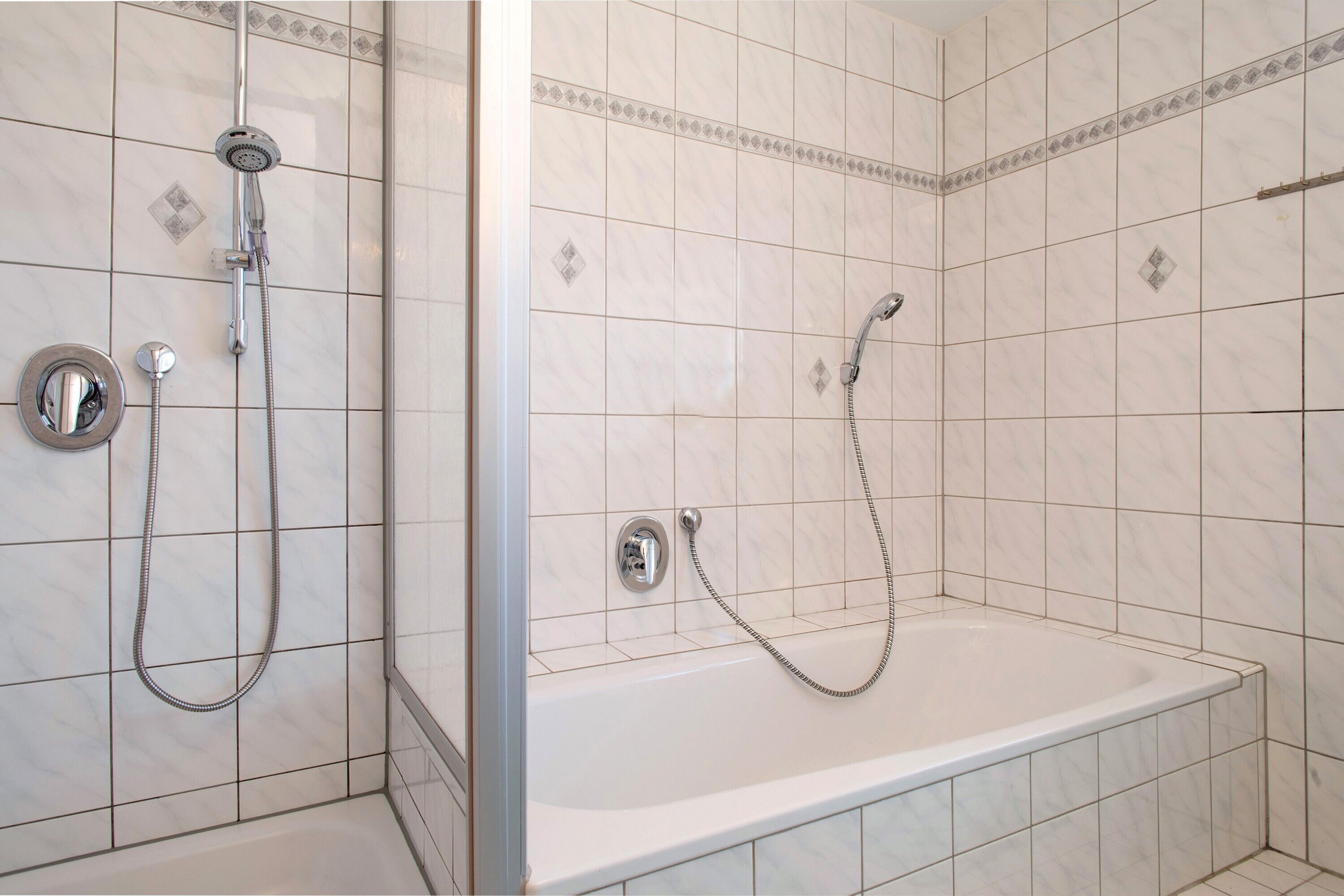 A bathroom with a shower, a bathtub, and tiled walls.