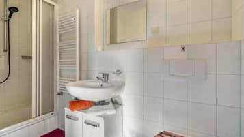 Un bagno con doccia, lavandino, specchio e porta asciugamani.