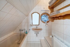 Een badkamer met een bad, een wastafel, een spiegel en een handdoekhouder.