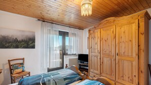 A bedroom with a bed, a chair, a TV, and a wardrobe.