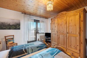 Une chambre à coucher avec un lit, une chaise, une télévision et une armoire.