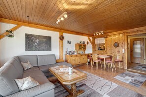 Una sala de estar acogedora con sofá, mesa de centro, techo de madera y juego de comedor.
