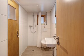 Un baño pequeño con ducha, inodoro y lavabo.