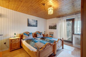 Un dormitorio con una cama de madera, mesitas de noche, una lámpara y vistas al exterior a través de una ventana.