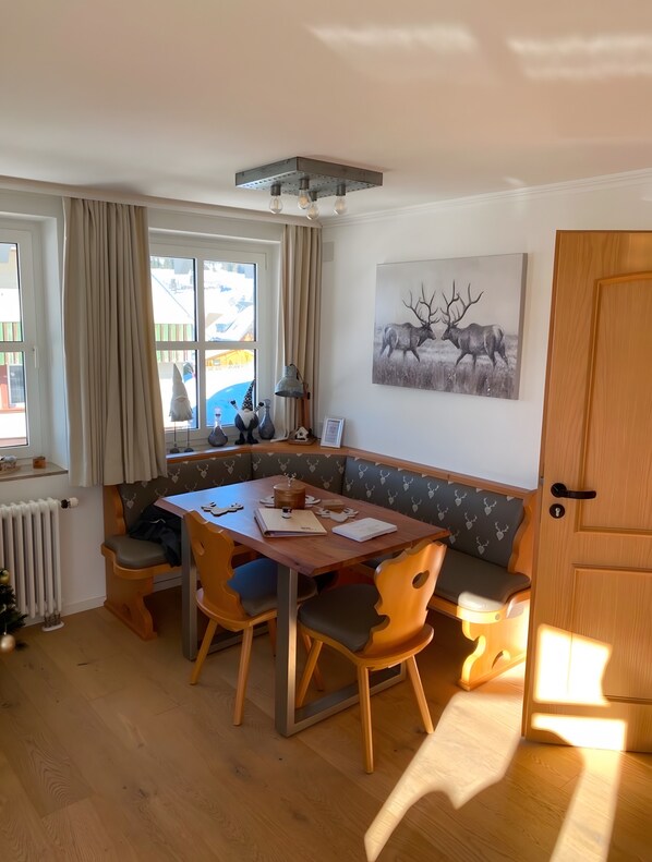 Ein gemütliches Zimmer mit Holztisch, Stühlen, einer Bank und einer Heizung.