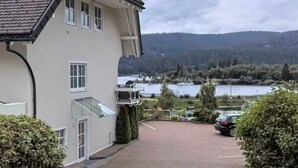 Un edificio con un camino pavimentado, vista a un lago y un coche estacionado al fondo.