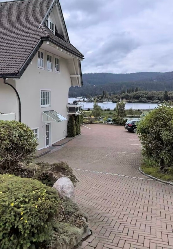 A building with a paved driveway, a view of a lake, and a car parked in the background.