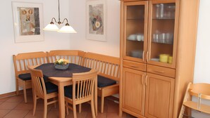 Un comedor con una mesa de madera, sillas, un armario y dos lámparas fijadas a la pared.