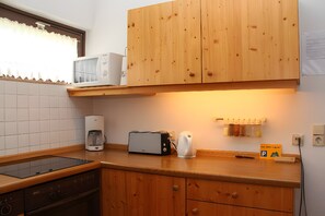 A kitchen with wooden cabinets, a microwave, a toaster, a coffee maker, and a sign indicating a parking area.
