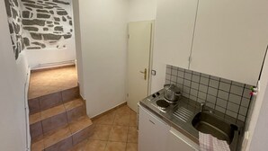 Une cuisine de taille réduite, équipée d’une cuisinière, d’un évier et d’un plan de travail recouvert de carreaux.