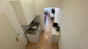 Une cuisine de taille réduite, équipée d’un évier, d’une cuisinière et d’un petit plan de travail.