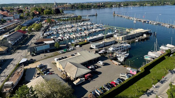 Un port de plaisance avec des bateaux amarrés, une gare et un bâtiment doté d’un toit en pente.